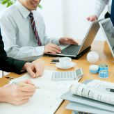 Colleagues sitting around desk surrounding business technology